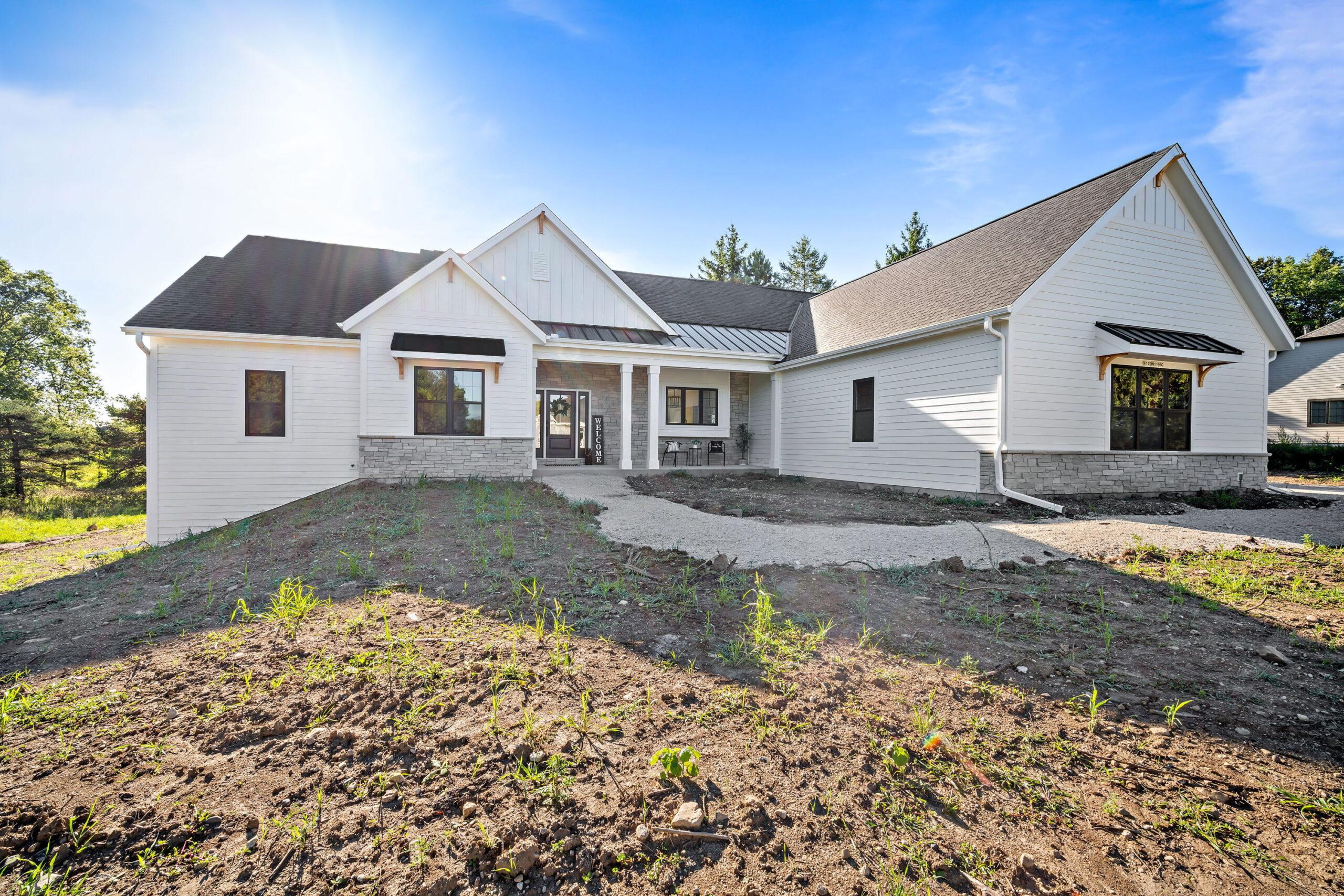 Modern farmhouse exterior with white siding, stone details, and covered front porch entry