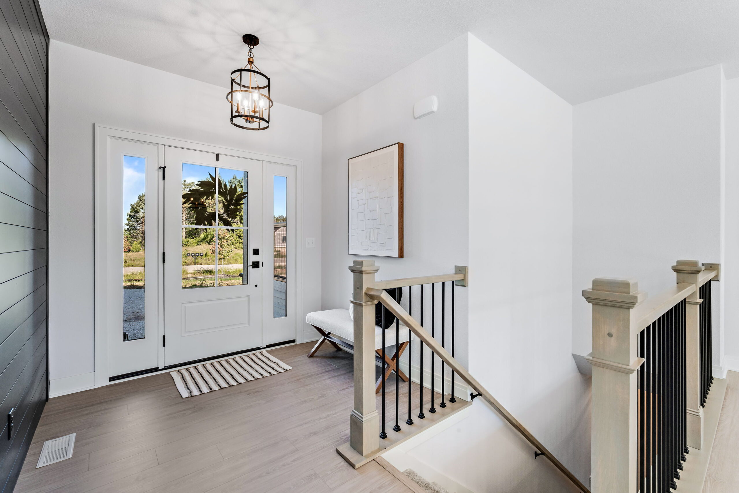Front entryway with staircase railing, glass front door, and natural light