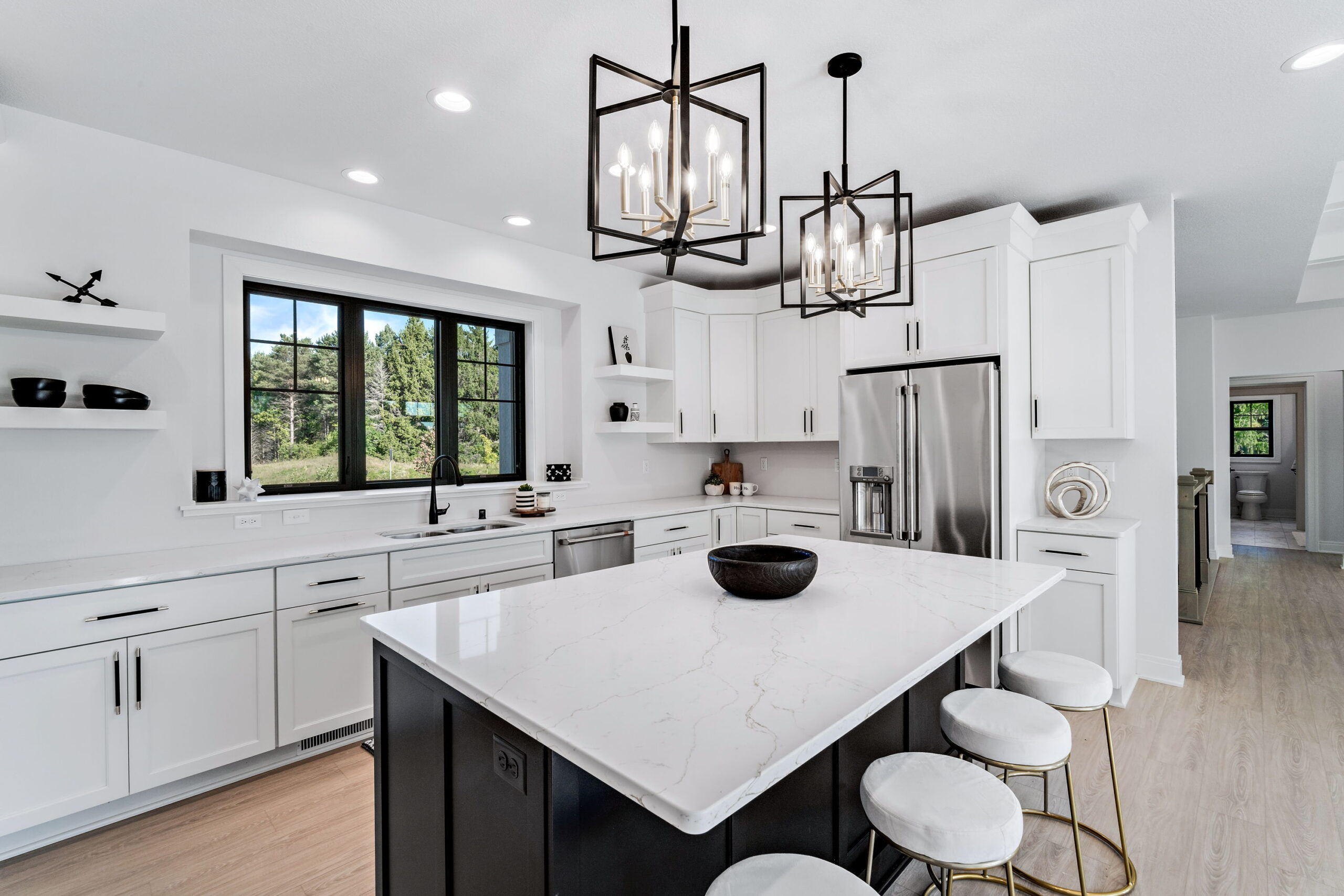 Bright kitchen with large island, white cabinetry, pendant lighting, and stainless steel appliances