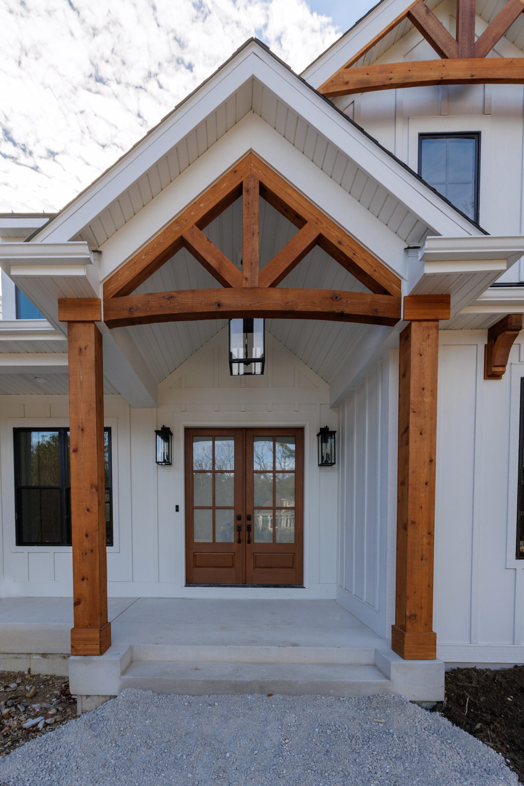Front entry of Merton home with timber frame porch, wood columns, and double front doors