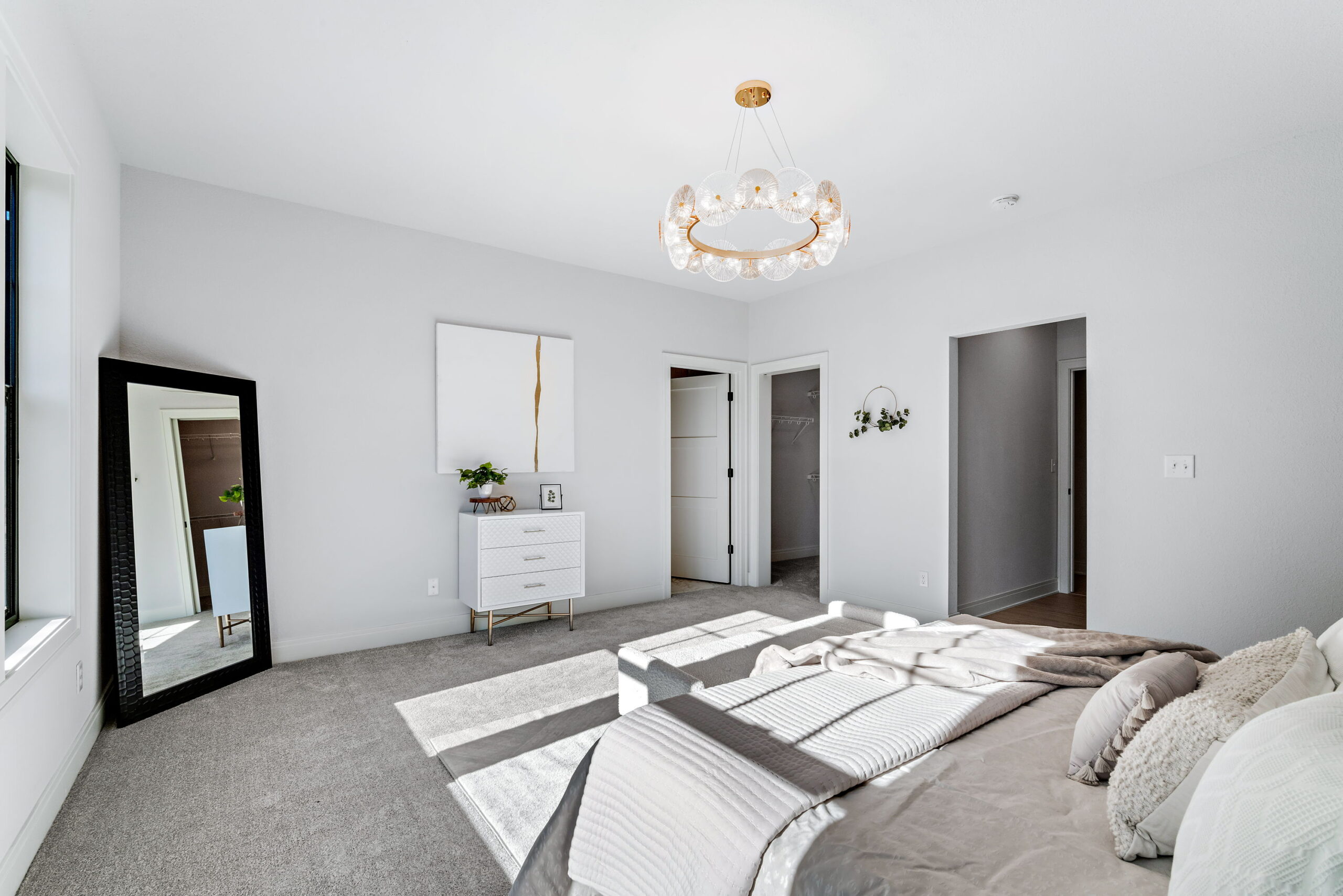 Primary bedroom with large windows, carpet flooring, modern lighting, and neutral finishes