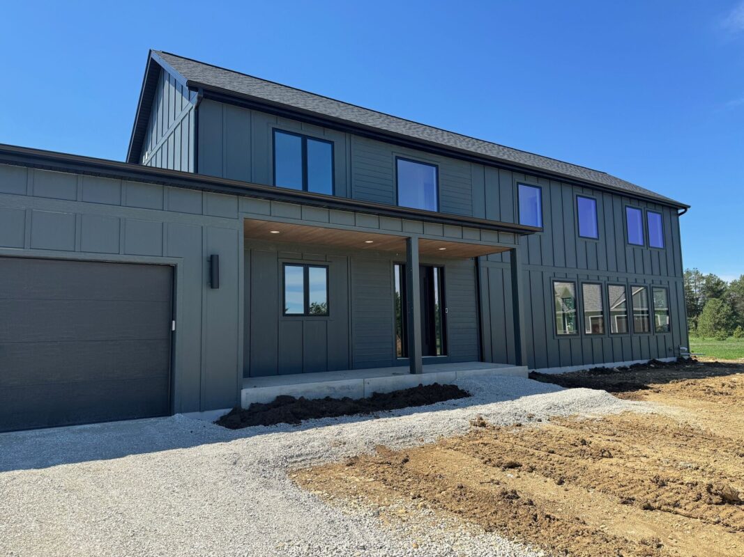 custom home front entry with covered porch, dark siding, and modern farmhouse design