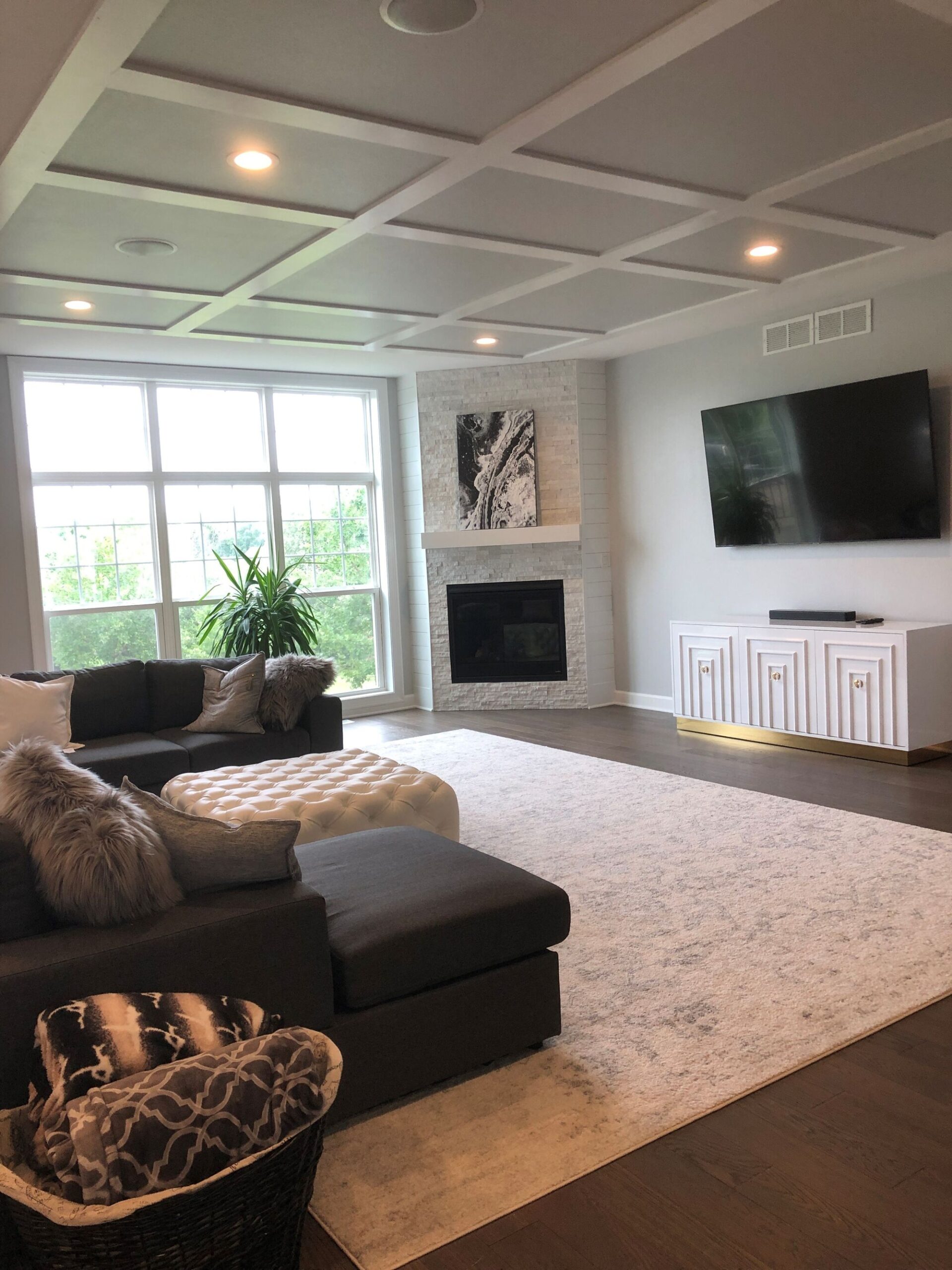 modern living room with coffered ceiling fireplace large window and mounted tv