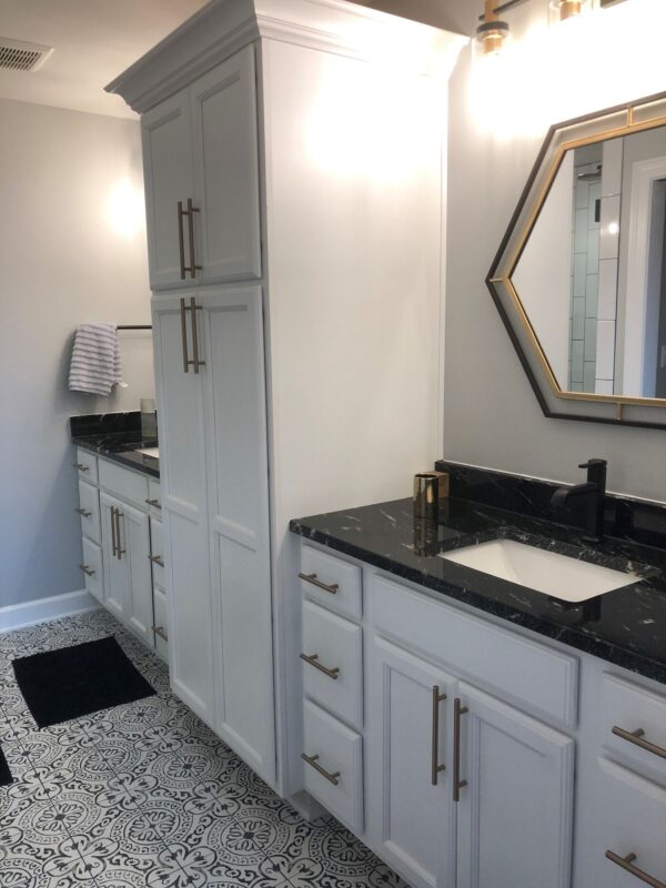 modern bathroom with white cabinets black countertop geometric mirror and patterned tile floor