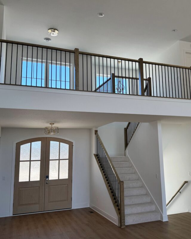 Morrow Home entryway with staircase, wood railing, and second floor overlook