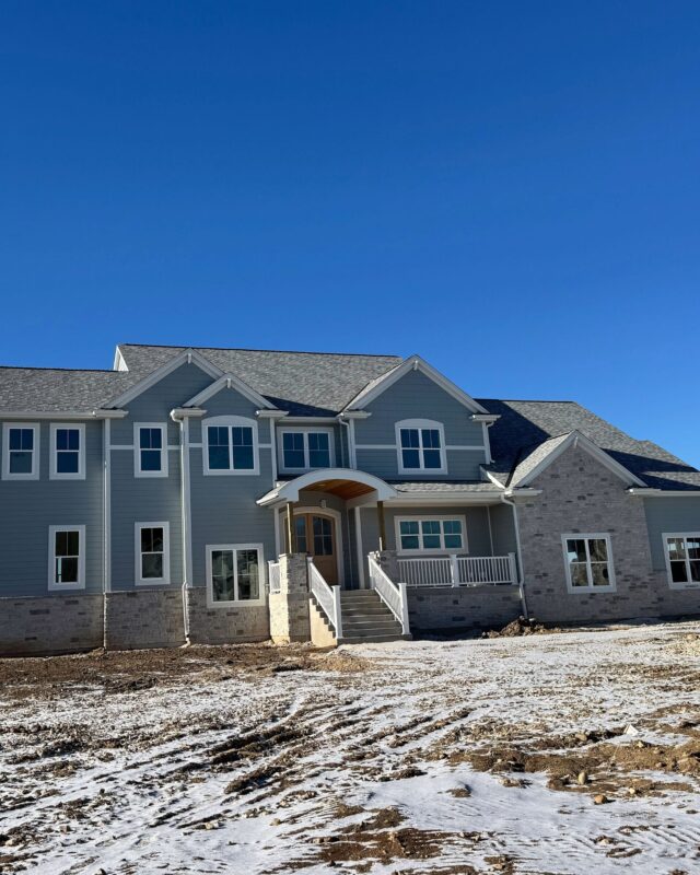 Morrow Home exterior with gray siding, stone accents, covered front porch, and gabled rooflines