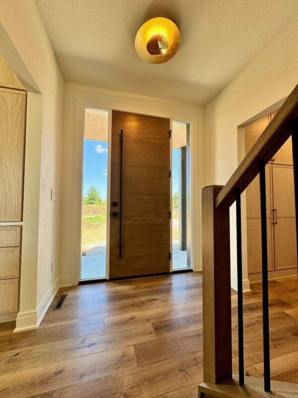 custom home foyer with wood front door, large windows, and staircase railing