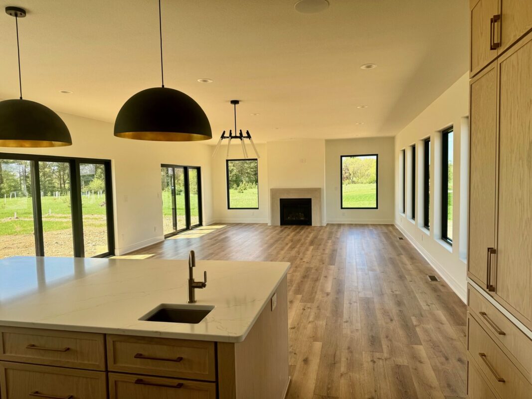 custom home open concept kitchen and living room with large windows, island, and fireplace