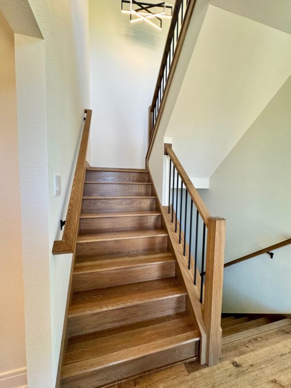 custom home wood staircase with black metal balusters and modern railing design