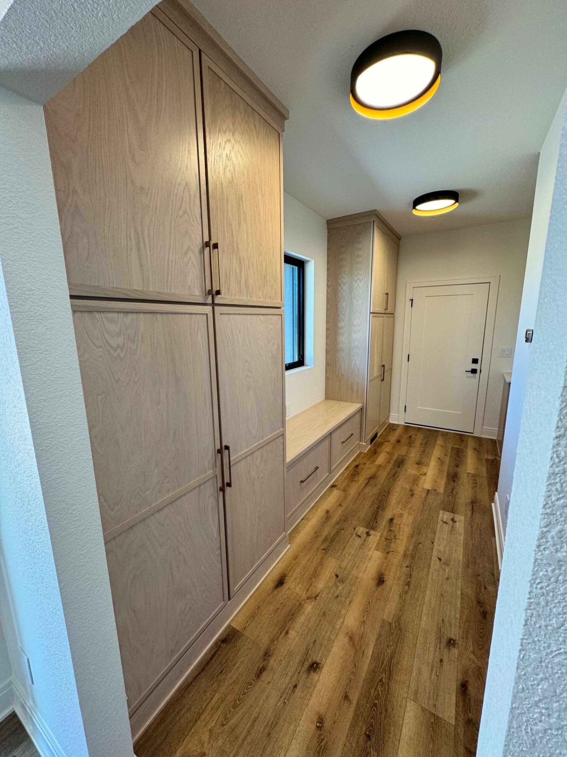 custom home mudroom with built-in cabinets, bench seating, and wood flooring