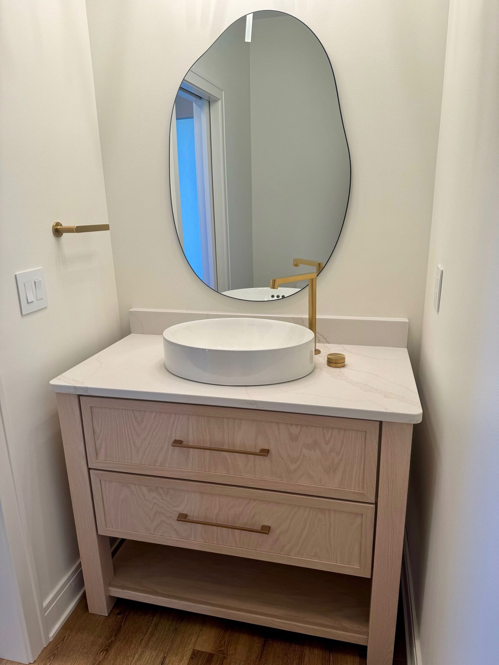 custom home powder room with wood vanity, vessel sink, and modern gold faucet